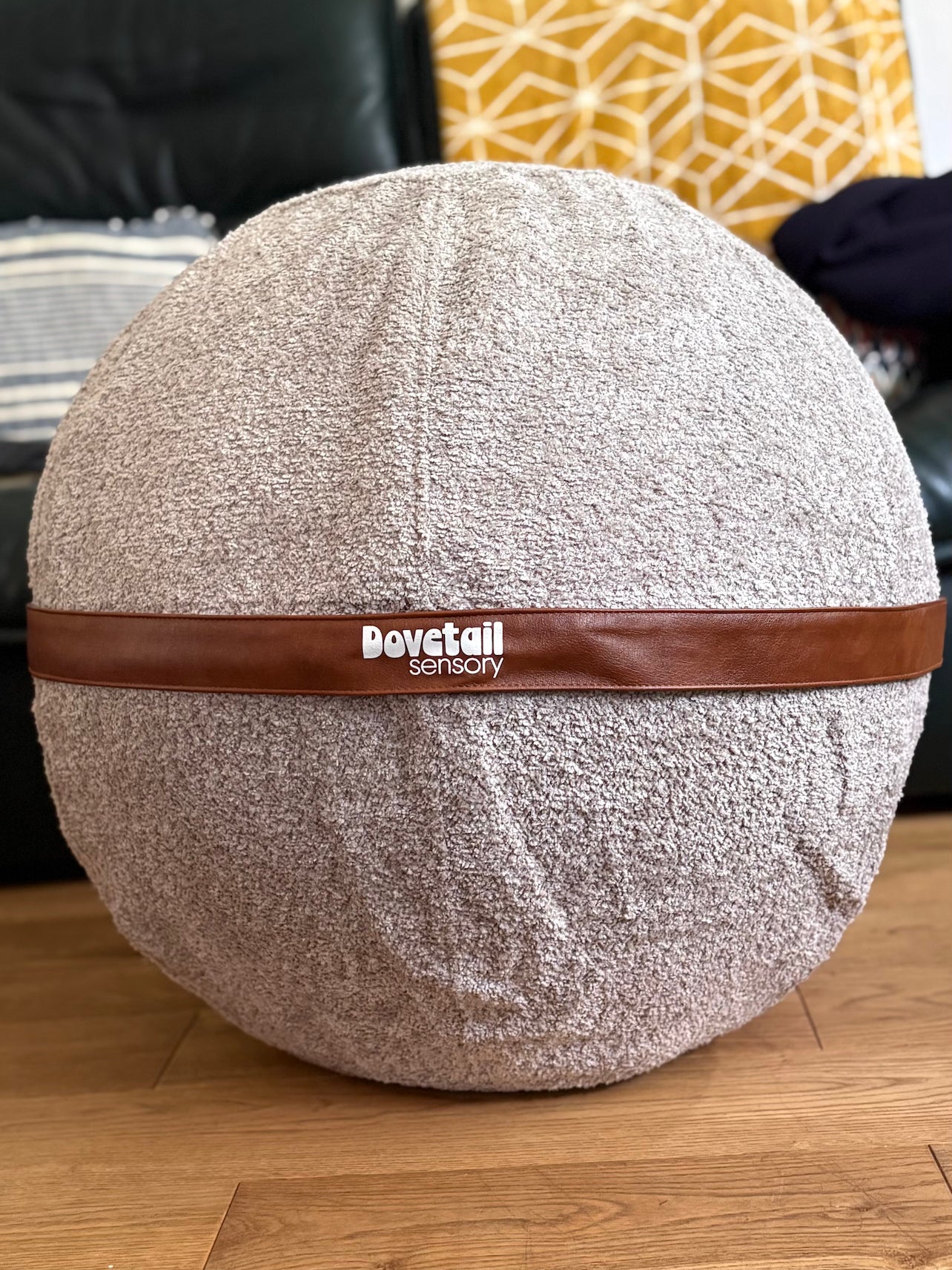 Round textured ball with a brown band and 'Dovetail sensory' branding on a wooden floor.