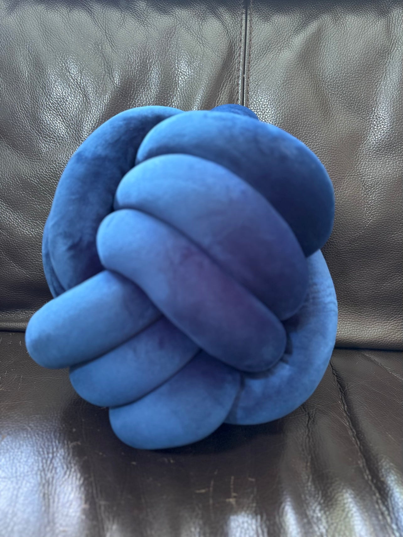 Blue Dovetail sensory knot pillow on a brown leather couch
