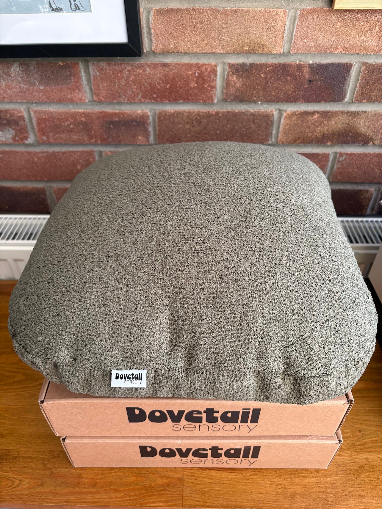 Gray cushion on a cardboard box with 'Dovetail Sensory' branding against a brick wall.