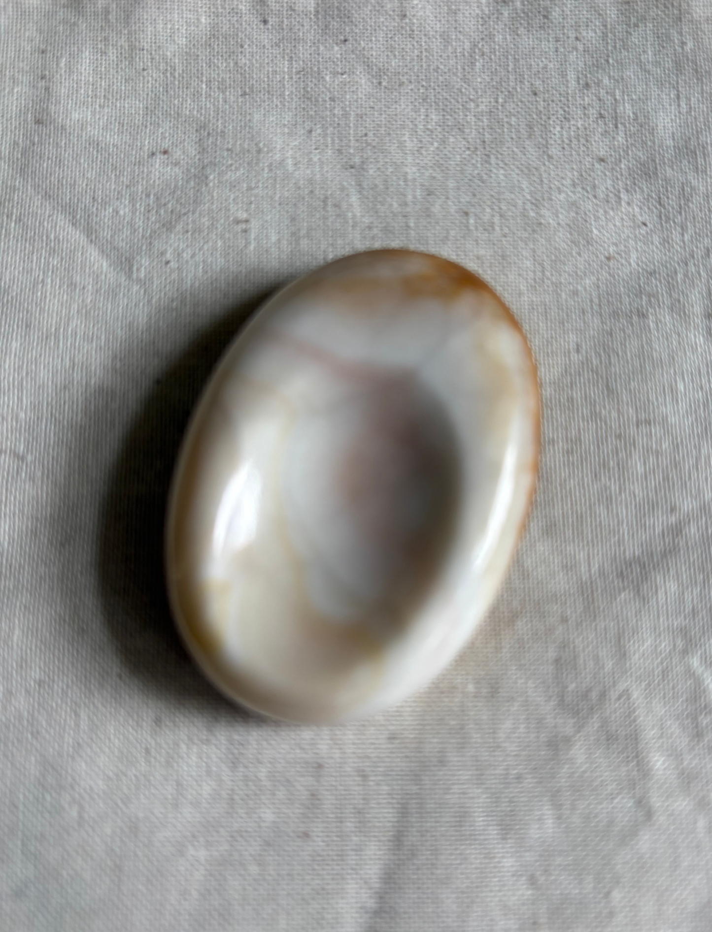 Oval-shaped stone on a textured beige fabric background