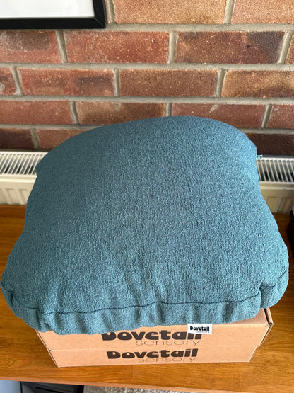 Blue cushion on a cardboard box with 'Dovetail sensory' branding against a brick wall.