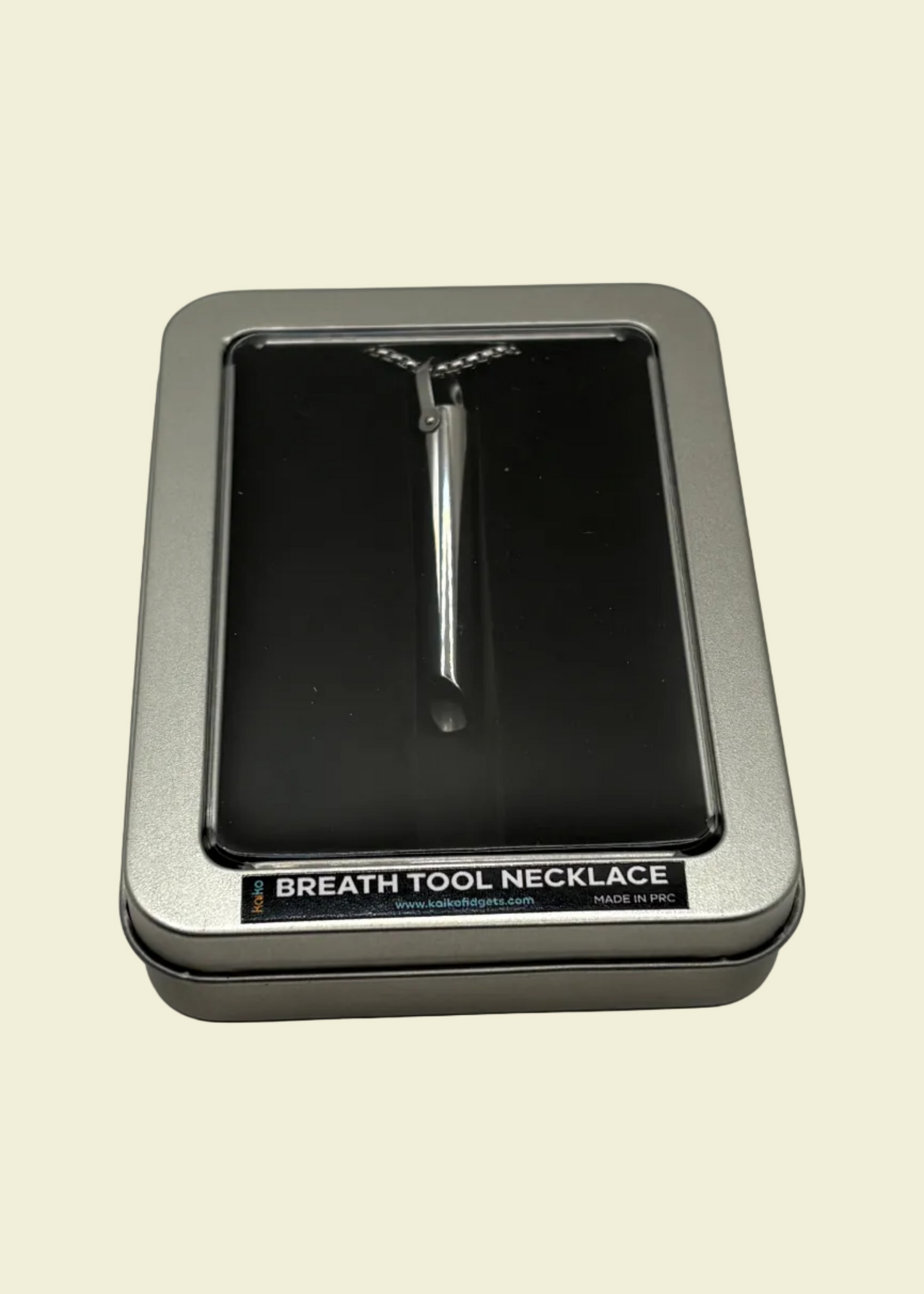 Breath tool necklace in a silver display case on a beige background