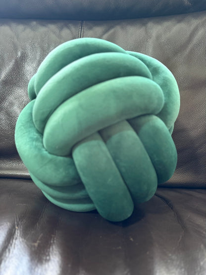 Green Dovetail sensory knotted pillow on a brown leather couch