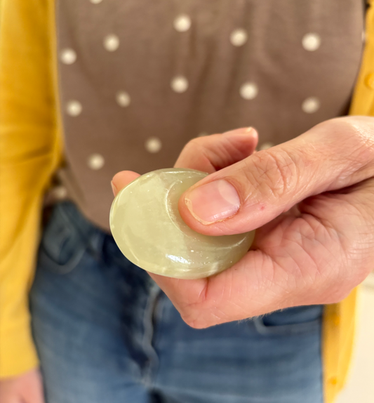 Person holding a green stone in their hand with a blurred background