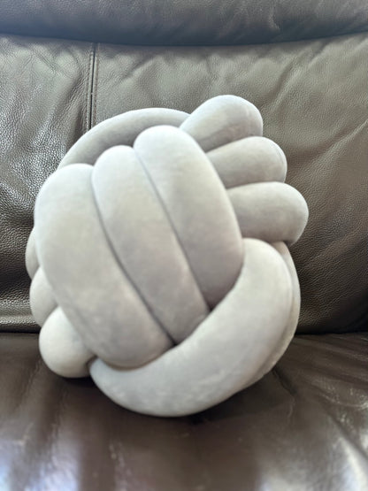 Grey Dovetail sensory knot pillow on a brown leather surface