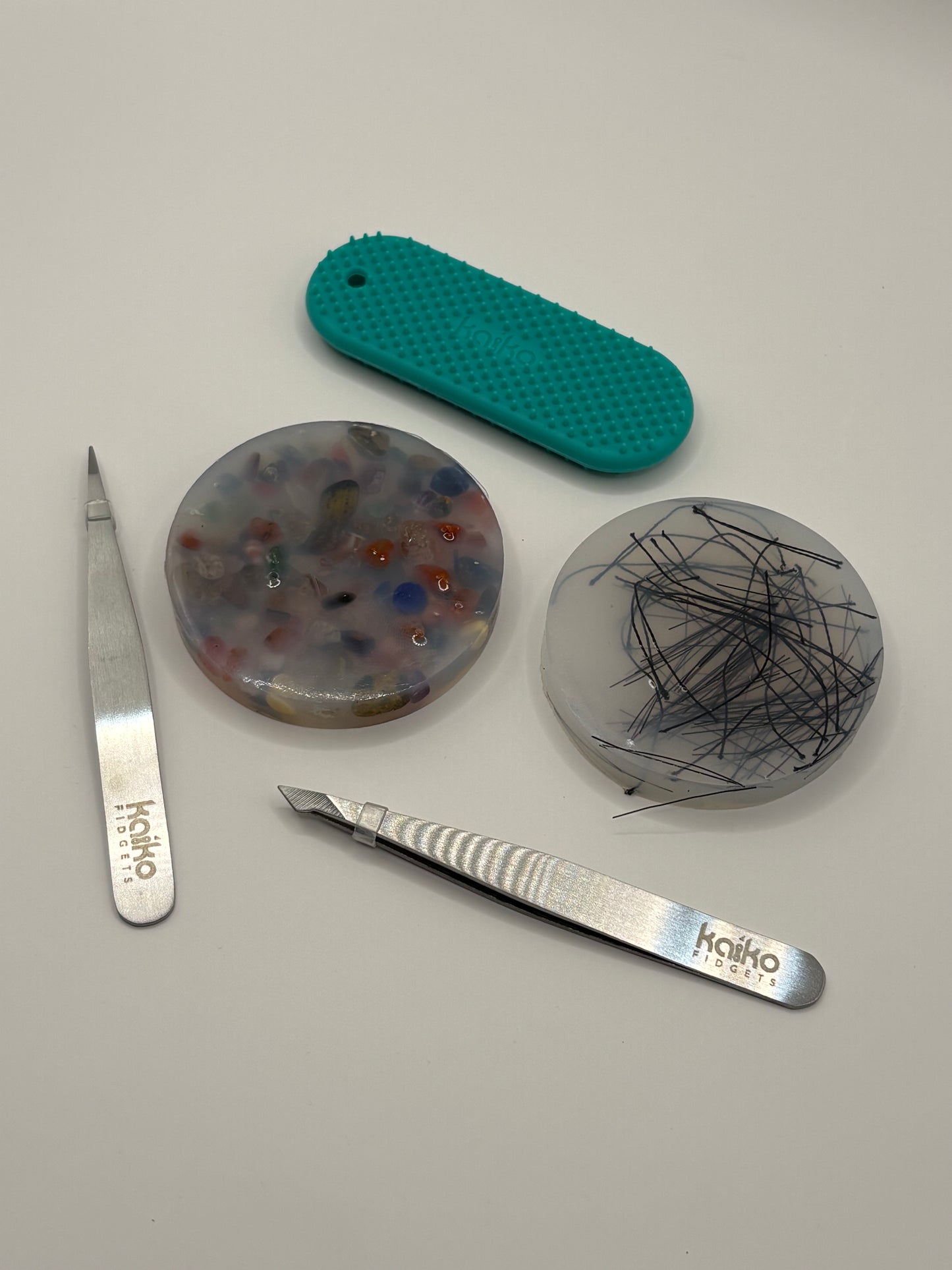 Two metal tools with 'kaiko' branding on a gray surface with three textured ceramic discs.