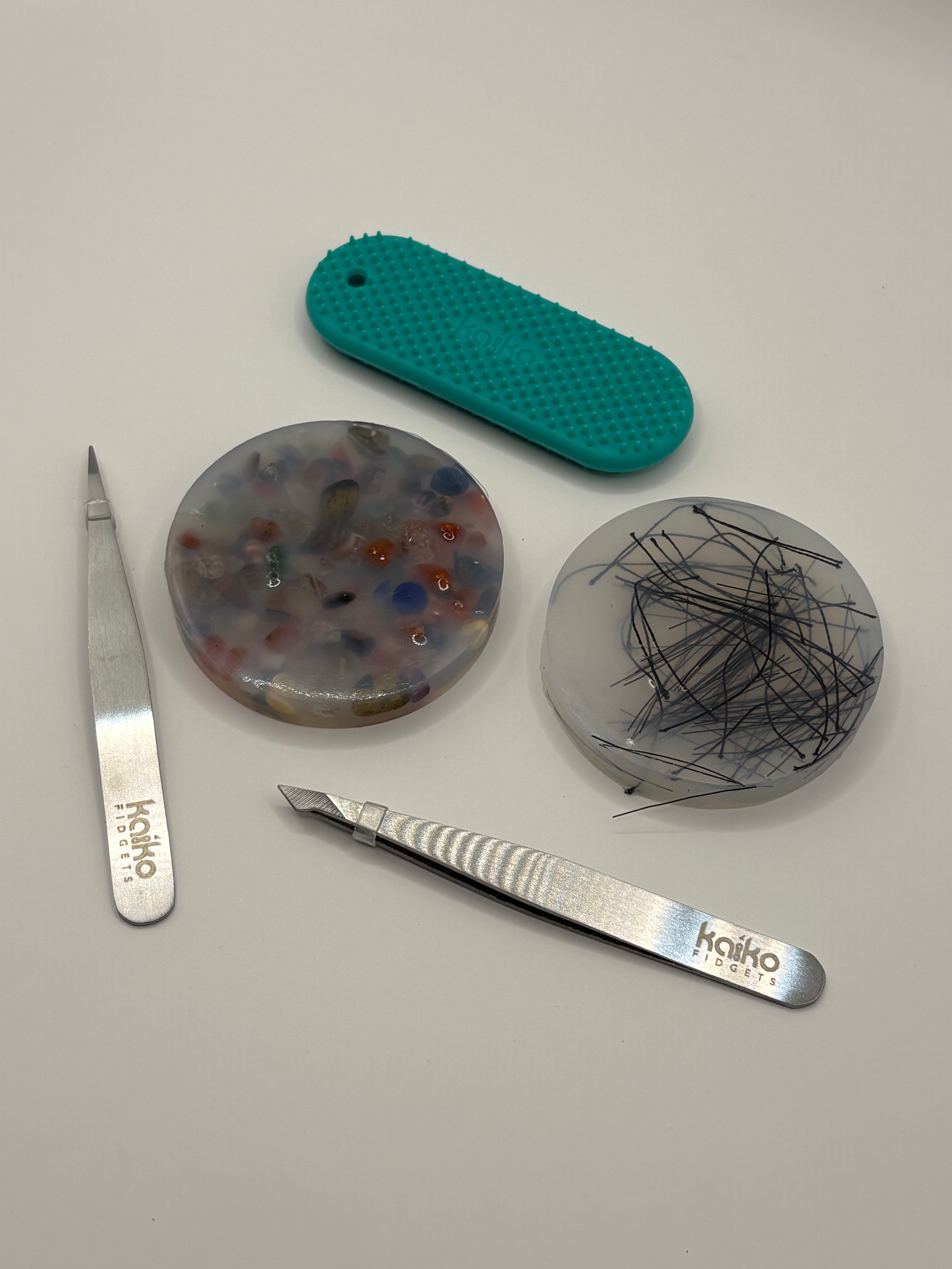 Two metal tools with 'kaiko' branding on a gray surface with three textured ceramic discs.