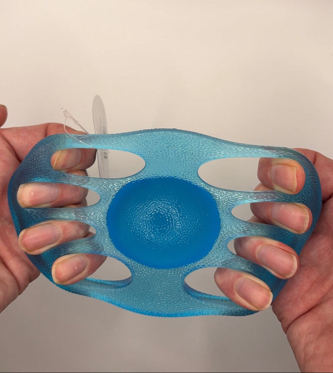 Blue textured ball held in a hand against a neutral background