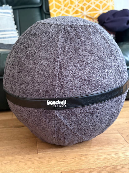 black textured ball with a black band labeled 'Dovetail sensory' branding on a wooden floor.