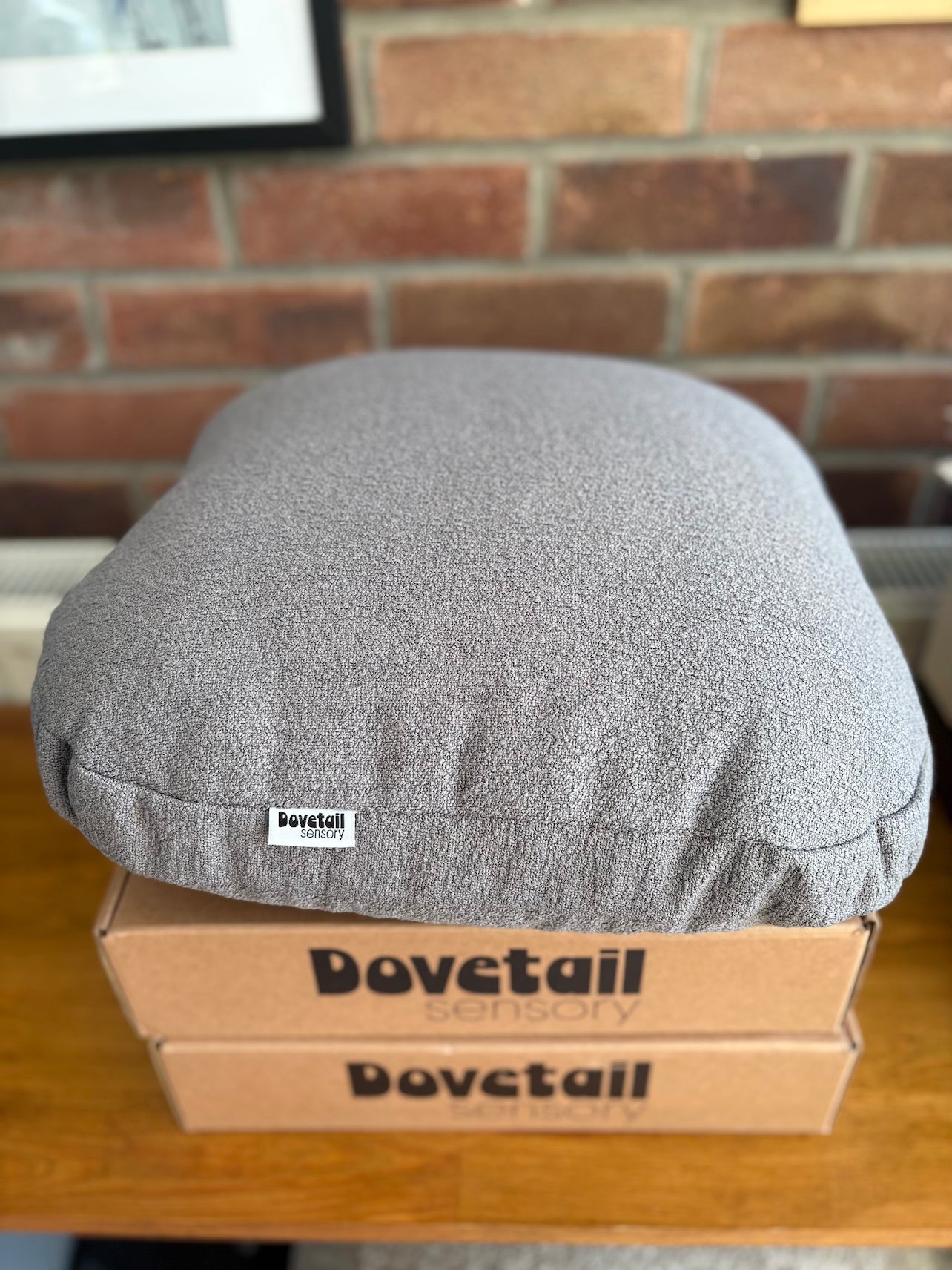 Gray cushion on a Dovetail Sensory box against a brick wall.