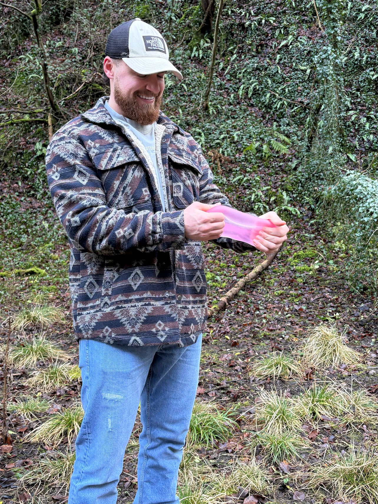 Man holding a pink speks gump in a forest setting