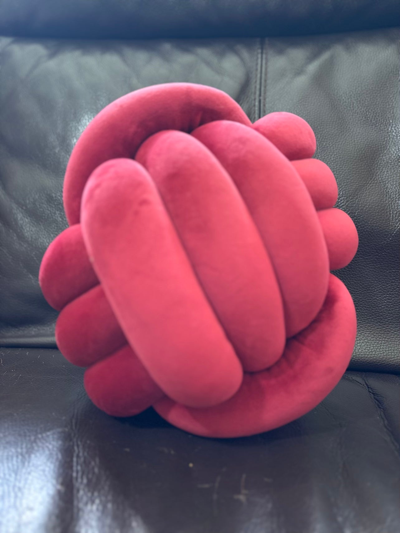 Red Dovetail sensory knot ball on a black leather surface